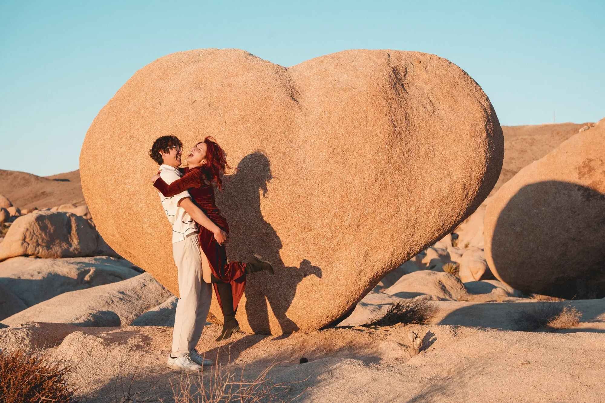 Los Angeles Couples Photographer — Couples Session at the Heart Rock in Joshua Tree Los Angeles couples photographer capturing a couple laughing and spinning together in front of the iconic heart-shaped boulder at Joshua Tree National Park at golden hour