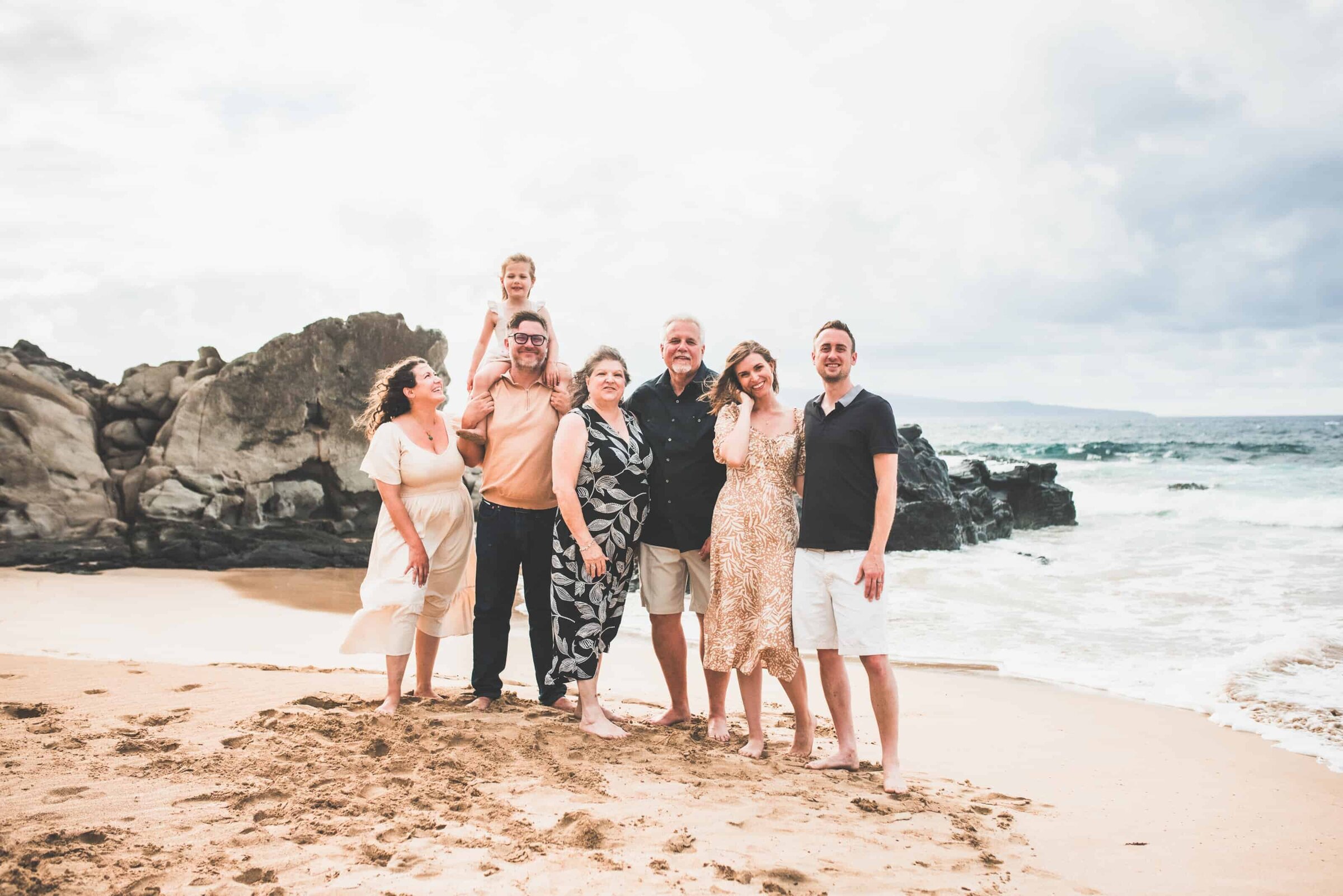 Multigenerational family on rocky beach Multigenerational family of seven on a rocky beach