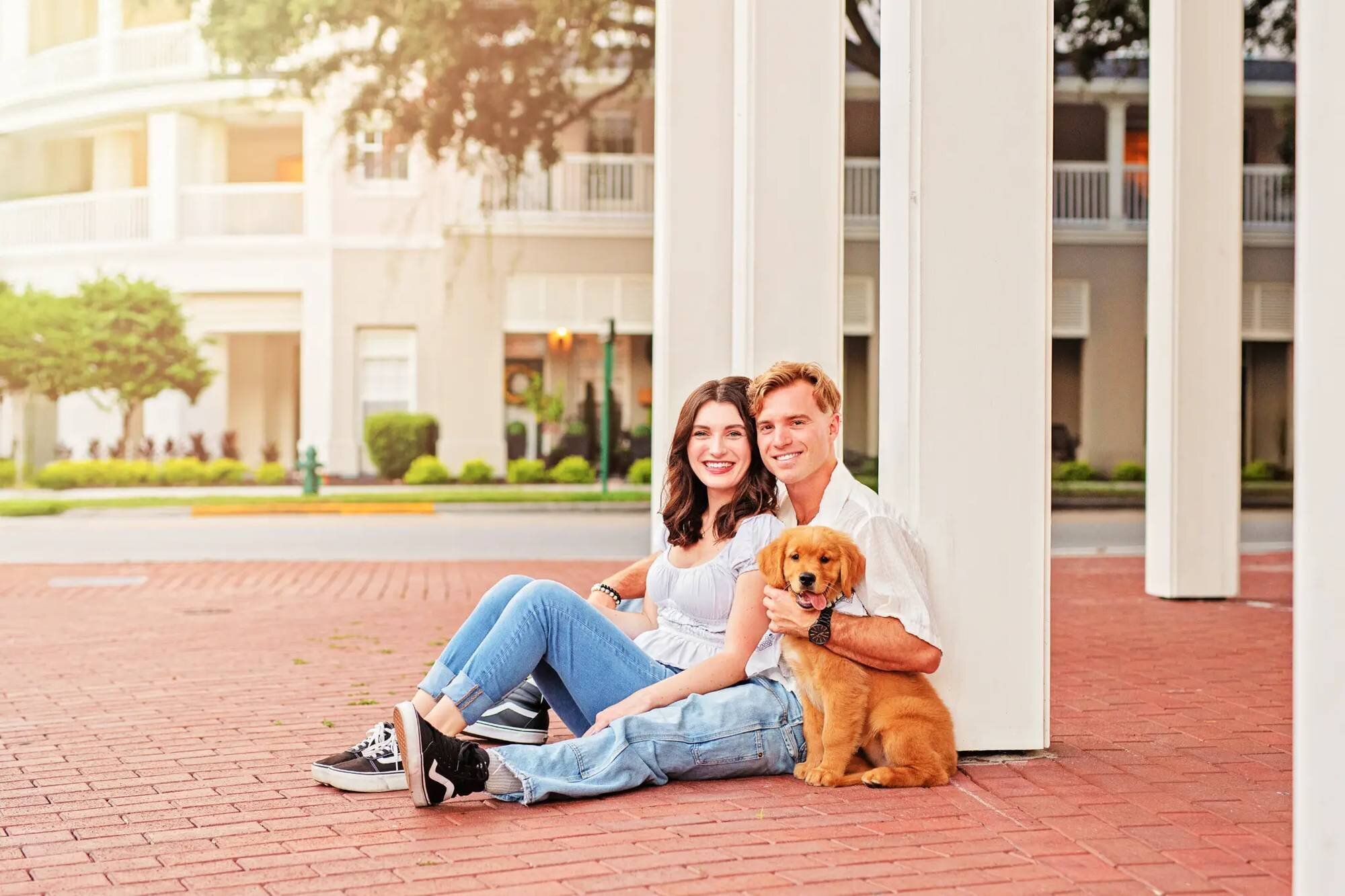 Couple with golden retriever puppy Young couple sitting with their golden retriever puppy outside a Disney resort hotel