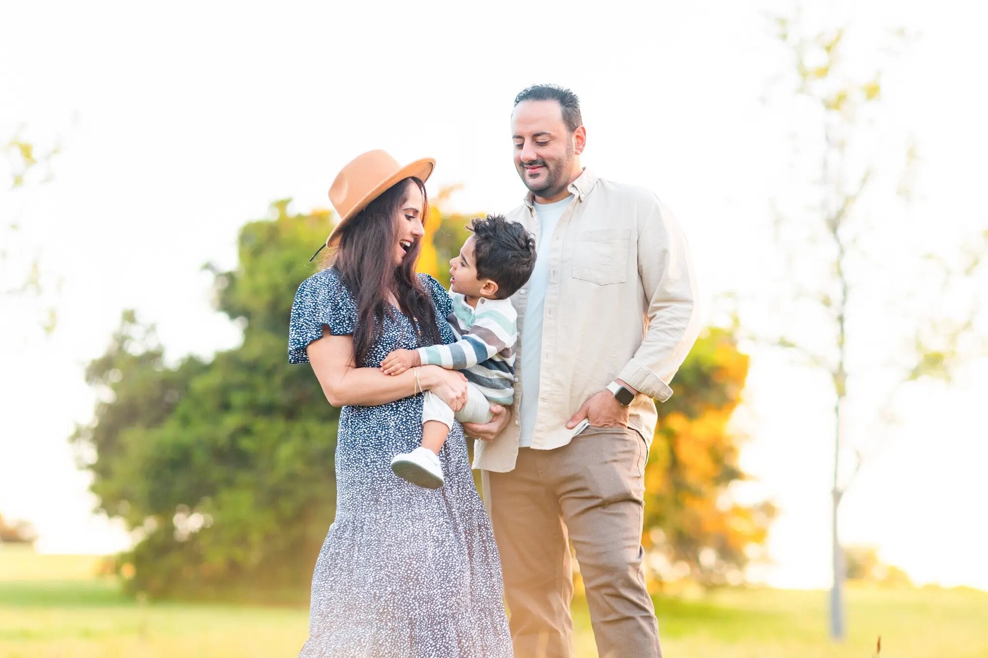 Los Angeles Family Photographer — Family Session at Kenneth Hahn State Recreation Area Los Angeles family photographer capturing a mother in a blue floral dress and wide-brim hat laughing with her toddler son while the father smiles beside them at Kenneth Hahn State Recreation Area