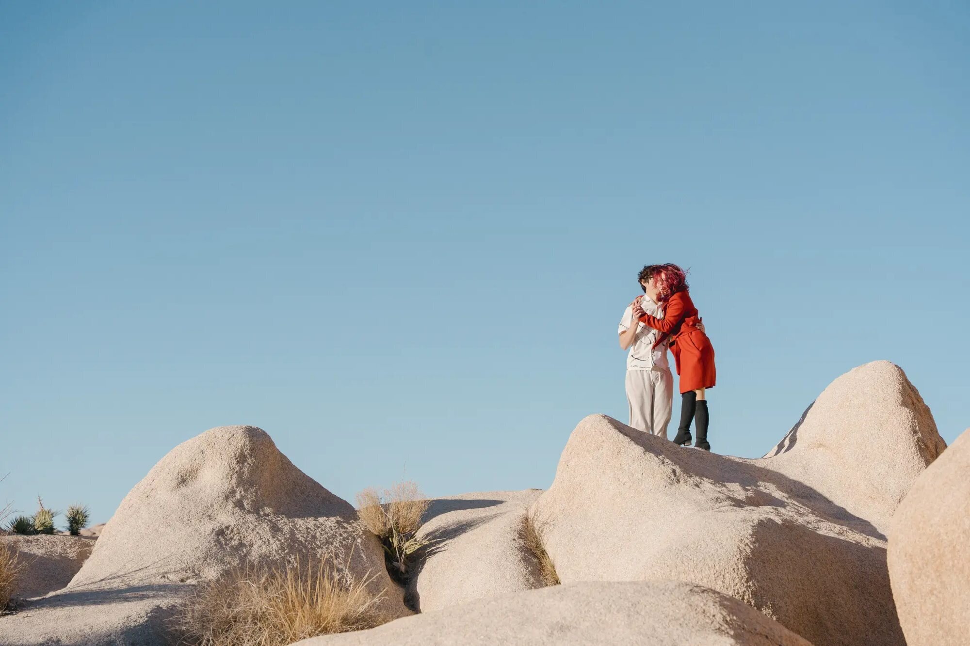 Los Angeles Couples Photographer — Couples Session at Joshua Tree National Park Los Angeles couples photographer capturing a couple embracing on top of large desert boulders at Joshua Tree National Park against a clear blue sky