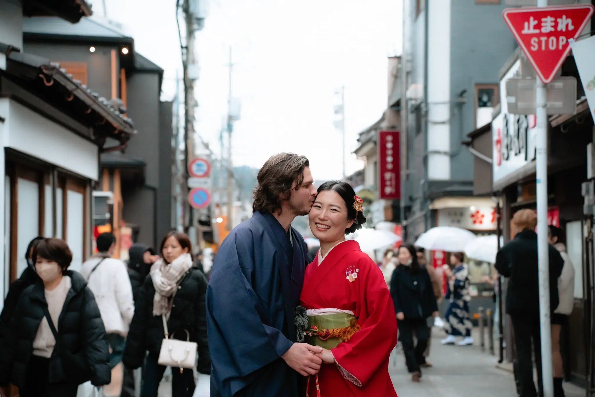 Fukuoka Photographer — Couple Kimono Session in Hakata A couple dressed in traditional Japanese kimono embracing on a busy street in Hakata, Fukuoka, during a professional couples photo session