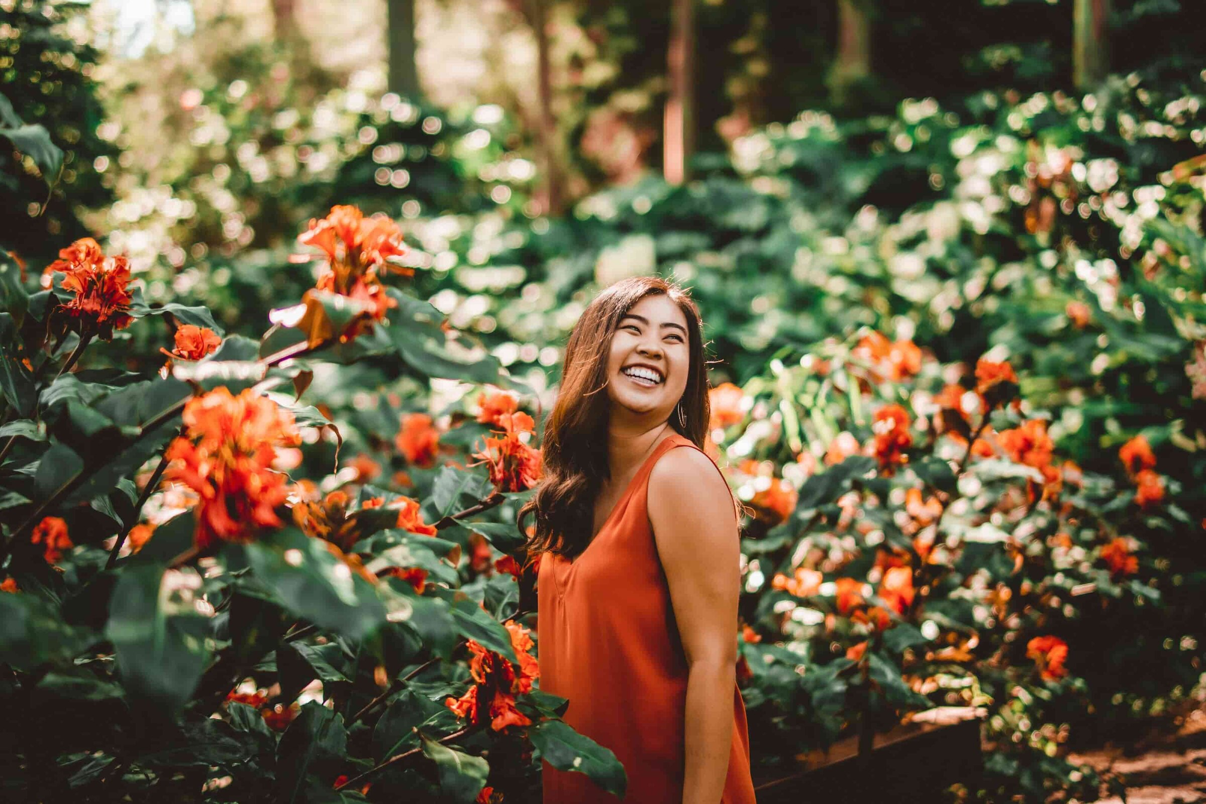 Woman laughing in garden Woman laughing in a tropical garden with orange flowers