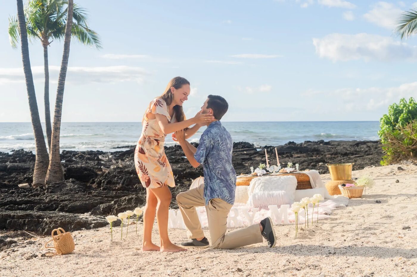 Proposal Photographer Big Island — Kona Beach Surprise Proposal A man proposing on one knee to his partner on a sandy Big Island beach with lava rocks and palm trees in the background