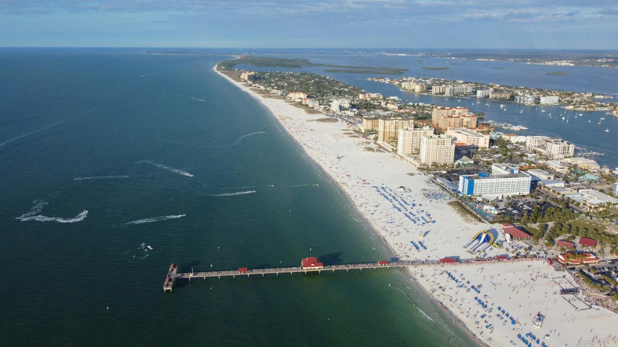 Tampa Photographer Locations | Clearwater Beach, Florida Aerial view of Clearwater Beach, Florida, showing the wide white sandy shoreline, turquoise Gulf waters, and beachfront hotels — a popular Tampa photo session location by Dreamgraphy