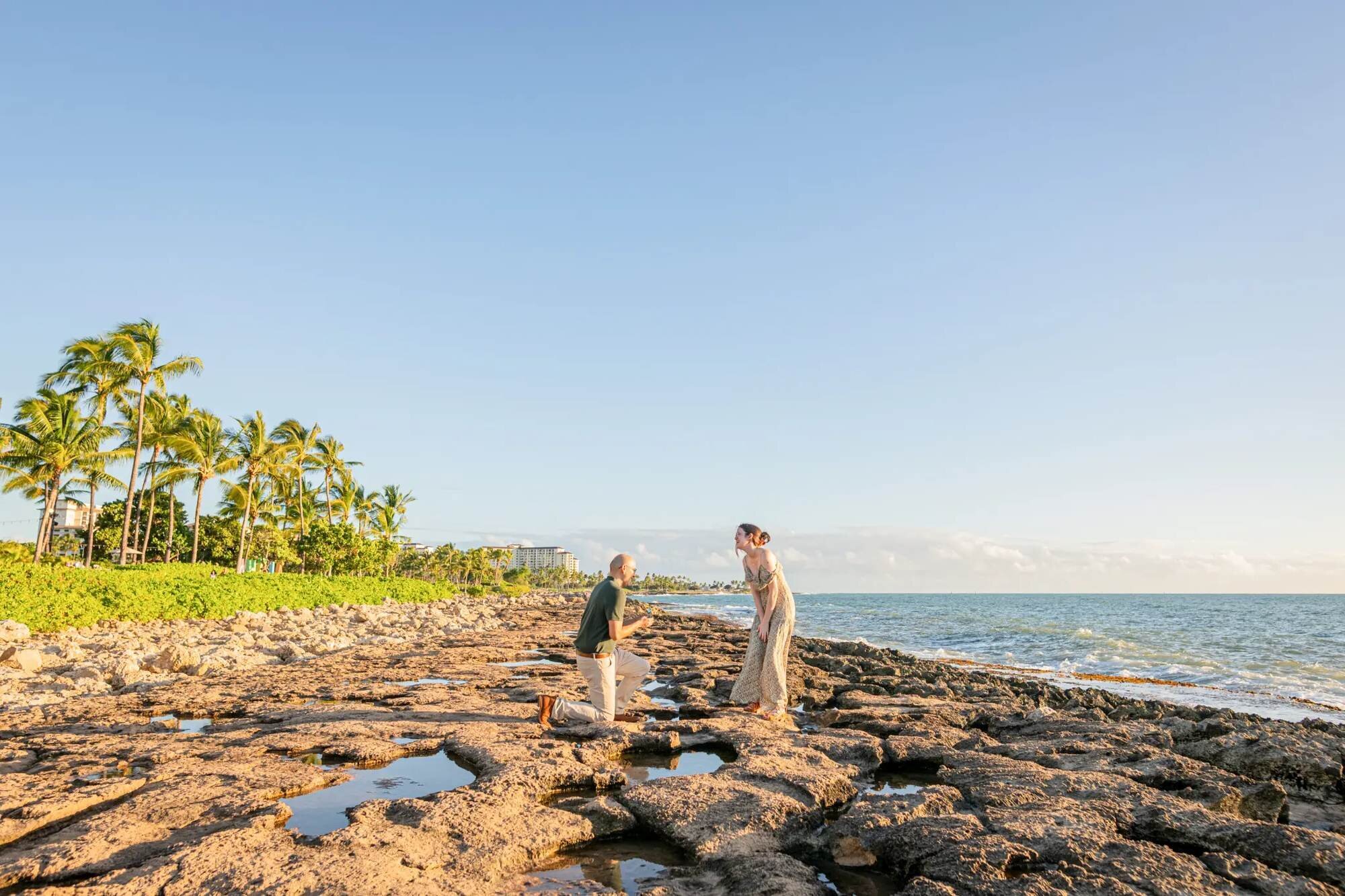 Couple during a surprise proposal on the rocky shoreline in Oahu