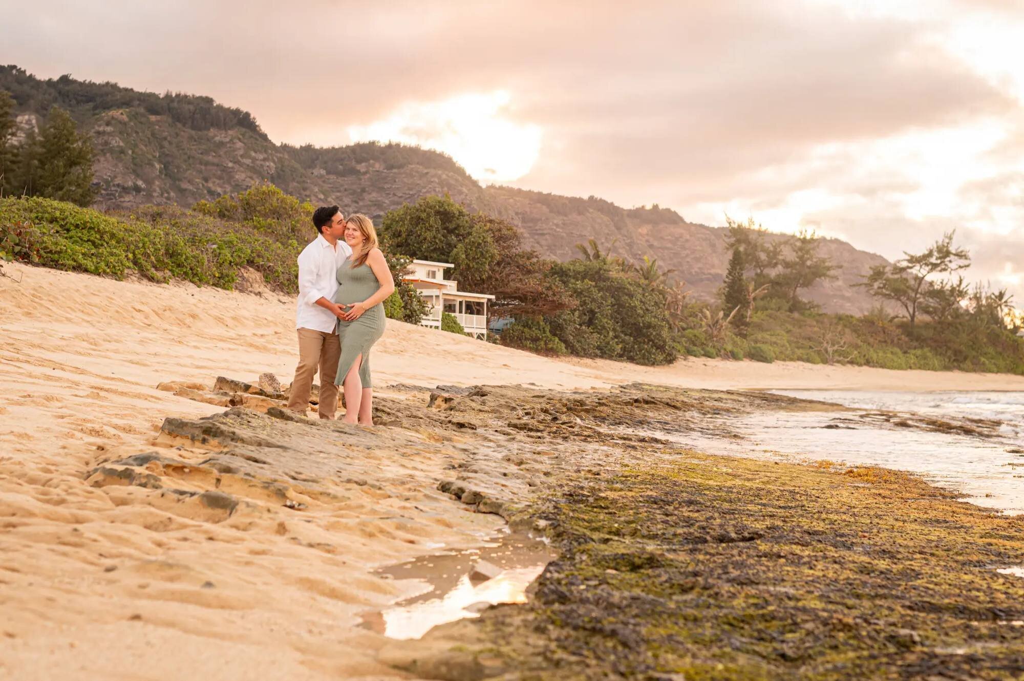 Couple embracing on a rocky North Shore beach at sunset during an Oahu engagement photo session