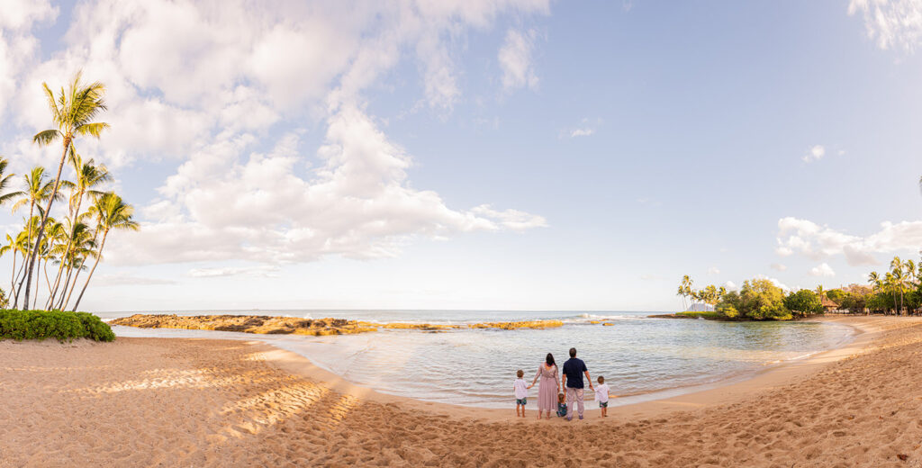A family enjoying a tranquil, private sunrise photoshoot on an empty Hawaiian beach, highlighting a key advantage of morning sessions.