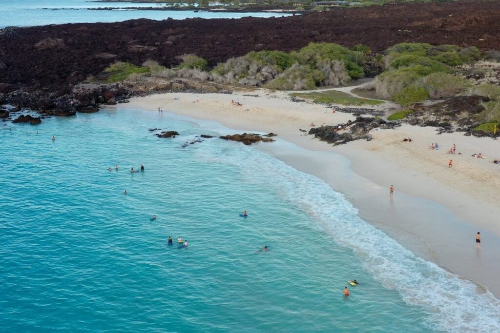Big Island family photoshoot location at Kua Bay featuring white sand and turquoise water.