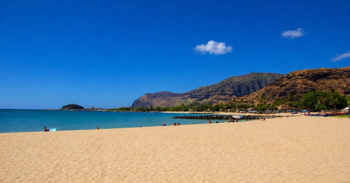 Pokai Bay Oahu, a live-action Moana filming location in Hawaii featuring calm water and green mountains.